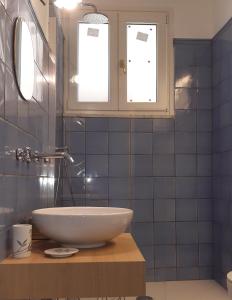 La salle de bains est pourvue d'un lavabo blanc et de carrelage bleu. dans l'établissement Salerno Eremita Apartment, à Salerne