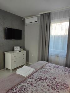 a bedroom with a bed with a dresser and a television at Flora Apartment in Surčin