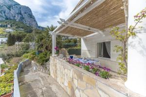 a white house with a stone wall with a table and flowers at Capri center holidays in Capri