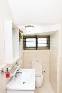 uma casa de banho com um WC branco e um lavatório. em Baldwin Beauty House em Accra