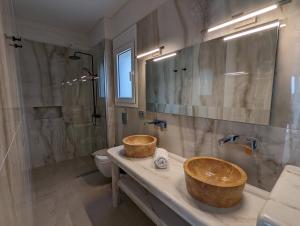 - une salle de bains avec 2 lavabos en bois sur un comptoir dans l'établissement Natura Luxury Suites Parga, à Parga