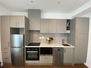 a kitchen with white cabinets and a stainless steel refrigerator at Modern, Central City, Penthouse Floor Apartment. in Auckland