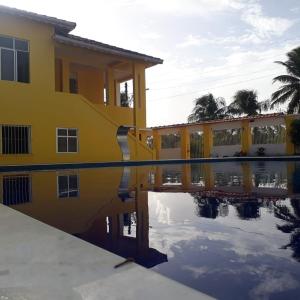 un edificio giallo con il suo riflesso in una piscina d'acqua di Suítes Soure a Soure