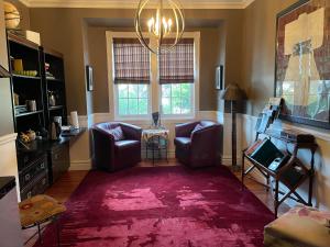 sala de estar con 2 sillas y alfombra roja en Globetrotters B&B, en Niagara on the Lake