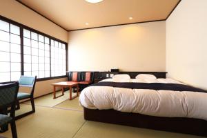 Schlafzimmer mit einem Bett, einem Stuhl und Fenstern in der Unterkunft Masuya Ryokan in Izumo