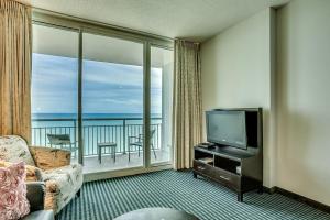 a living room with a television and a balcony at Fabulous Ocean Front Penthouse Condo, OO Resort, 21st Fl in Myrtle Beach