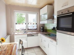 a kitchen with white cabinets and a sink and a window at Quiet apartment along a stream in Halenfeld in Sellerich