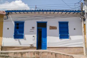 une maison blanche avec des fenêtres bleues et une porte bleue dans l'établissement Meraki Boutique Hostel, à San Gil