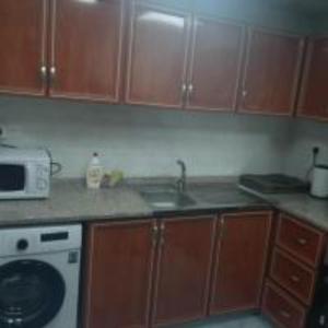 a kitchen with wooden cabinets and a sink and a microwave at Lemas 901 in Ajman 