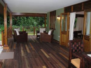 sala de estar con suelo y sillas de madera y balcón en Casa Verde, en Grand'Anse Praslin