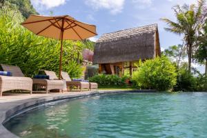 a pool with chairs and an umbrella next to a house at Like living in a romantic Balinese painting in Sidemen