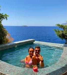 a man and a woman sitting in a swimming pool at Mandalina Suites in Kaş