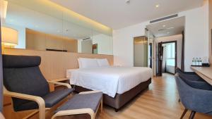 a hotel room with a bed and two chairs at Mintel Huamark in Bangkok