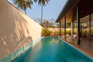 a swimming pool in front of a house at Bella Norma with Pool - North Goa at StayVista in Calangute