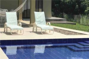 2 sillas sentadas junto a una piscina en LINDA CASA/PISCINA/VISTASUPERWIFI/DIRECTV/12PERSONAS, en Anapoima