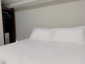 a bed in a room with white sheets and pillows at Hotel Calmo Chinatown in Singapore