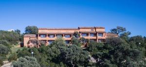 un gran edificio en la cima de una colina con árboles en Two-room apartment for 4 people with air conditioning 500 m from the sea near Porto Vecchio, en Zonza