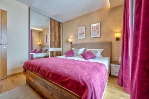 a bedroom with a large bed with a purple blanket at Apartman 65 Zlatibor in Zlatibor