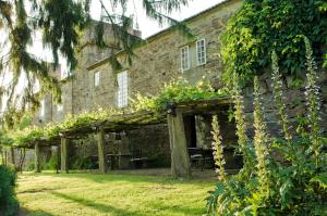 una antigua casa de piedra con un jardín delante de ella en Pazo de Andeade, en Andeade