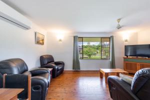 a living room with leather chairs and a flat screen tv at Compton House in Iluka