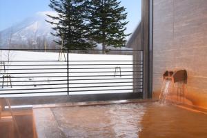 a room with a large window with water pouring into it at NISEKO Inn of Youtei Raku Suisan in Kutchan