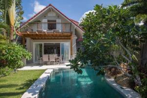 a villa with a swimming pool in front of a house at Beachfront Villa Charmant With Private Pool in Koh Samui