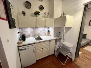 a kitchen with white cabinets and a sink and a chair at Cseri Porta in Szalafő