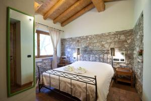 - une chambre avec un grand lit et un mur en pierre dans l'établissement Agriturismo BioBiò, à Vobarno