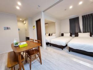 una camera d'albergo con due letti e un tavolo in legno di PRISM Inn Kamata a Tokyo