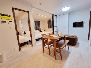 uma sala com uma mesa e um sofá e um quarto em PRISM Inn Kamata em Tóquio