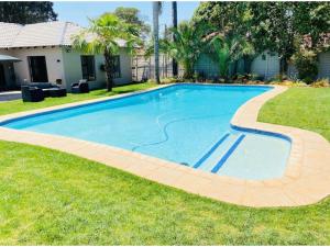 a swimming pool in the grass next to a house at Furaha Guest Lodge in Johannesburg
