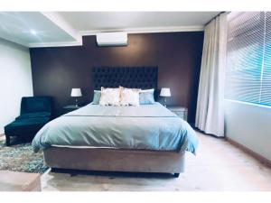 a bedroom with a large bed and a chair at Furaha Guest Lodge in Johannesburg