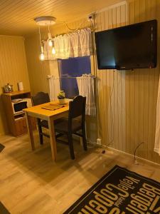 a dining room with a table and a flat screen tv at Koselig studioleilighet i Svolvær - Lofoten ved Svolværgeita, Djevelporten in Svolvær