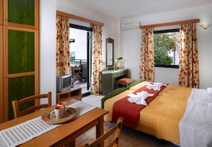 a hotel room with a bed and a table and a table and chairs at Erivolos Studios & Apartments in Lygaria