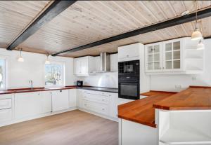 a kitchen with white cabinets and a wooden ceiling at Lundø in Højslev