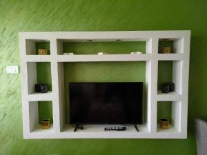 a white shelf with a tv on a green wall at Apartman Zelenika in Banja Koviljača +22 photos