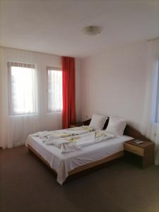 a bedroom with a large bed with a red curtain at Ivet Guest House in Obzor