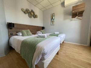 - une chambre avec 2 lits avec des draps verts et blancs dans l'établissement Hotel Le Rochegude, à Albi