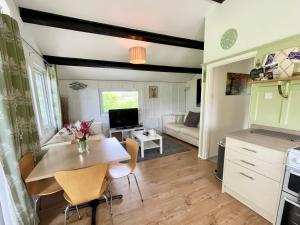 a kitchen and living room with a table and chairs at Beech Hut - a streamside family escape near Salcombe and Beaches in South Milton