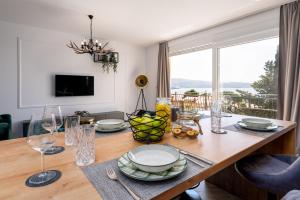 einen Esstisch mit Tellern und Gläsern sowie ein Fenster in der Unterkunft Deluxe apartment Skyline - fantastic sea view near the beach in Krk