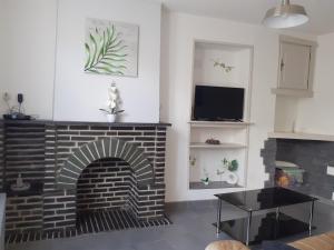 sala de estar con chimenea de ladrillo y TV en La maison du bonheur en Fumay