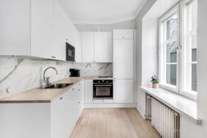 een witte keuken met witte kasten en een wastafel bij WeHost Modern Scandinavian Studio in Trendy Kallio in Helsinki