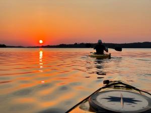 a man in a kayak on a lake at sunset at Hidden Island Laukanharju Glamping in Savonlinna
