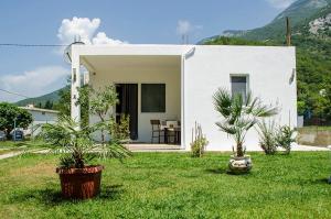 ein weißes Haus mit zwei Pflanzen im Hof in der Unterkunft Holiday Home Oaza in Čanj