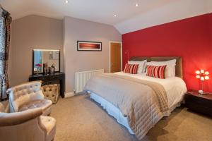 a bedroom with a large bed with a red wall at The Bondgate Boutique in Alnwick
