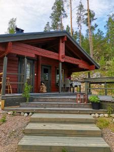 eine rote Hütte mit einer großen Holzterrasse in der Unterkunft Hidden Island Laukanharju Glamping in Savonlinna