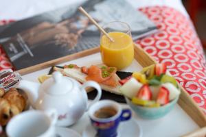 een dienblad met ontbijtproducten en een glas sinaasappelsap bij Grand Place Hôtel "Boutique et Appart'hôtel" in Arras