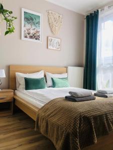 a bedroom with a bed with green curtains and a window at Apartament słoneczny in Olsztyn
