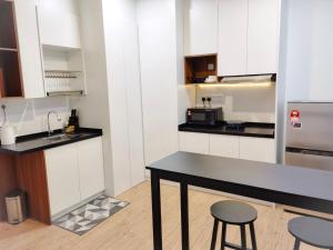a kitchen with white cabinets and a table and stools at The Parkville - Bangsar Trade Centre in Kuala Lumpur