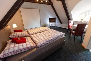 a bedroom with two beds with red pillows and a table at Pension Altes Burghotel in Neustadt-Glewe
